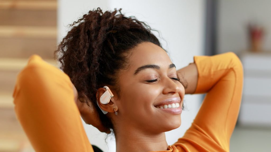 Woman wearing white Cleer Audio ARC 5 open-fit wireless earbuds lifestyle