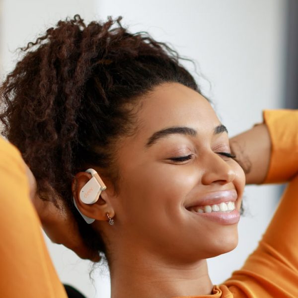 Woman wearing white Cleer Audio ARC 5 open-fit wireless earbuds lifestyle