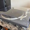 Denon DP-500BT Bluetooth Turntable sits on a marbled table next to a black speaker