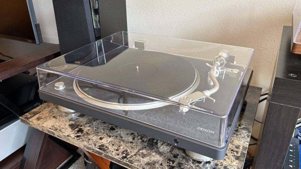 Denon DP-500BT Bluetooth Turntable sits on a marbled table next to a black speaker