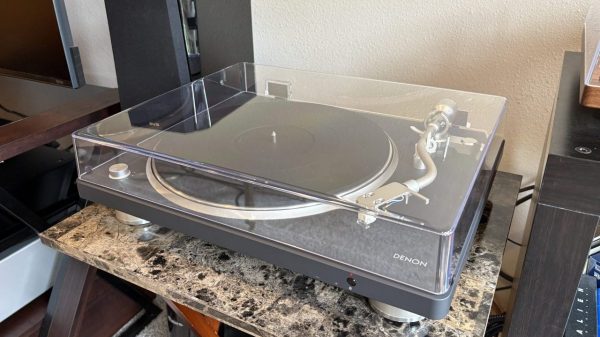 Denon DP-500BT Bluetooth Turntable sits on a marbled table next to a black speaker