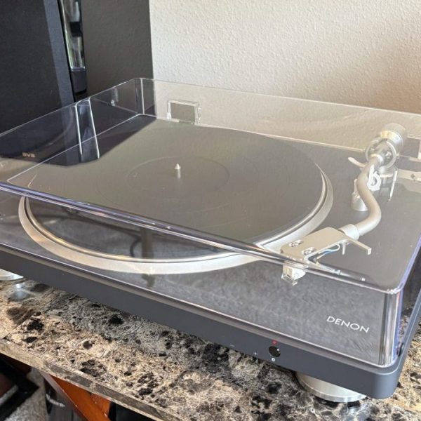 Denon DP-500BT Bluetooth Turntable sits on a marbled table next to a black speaker