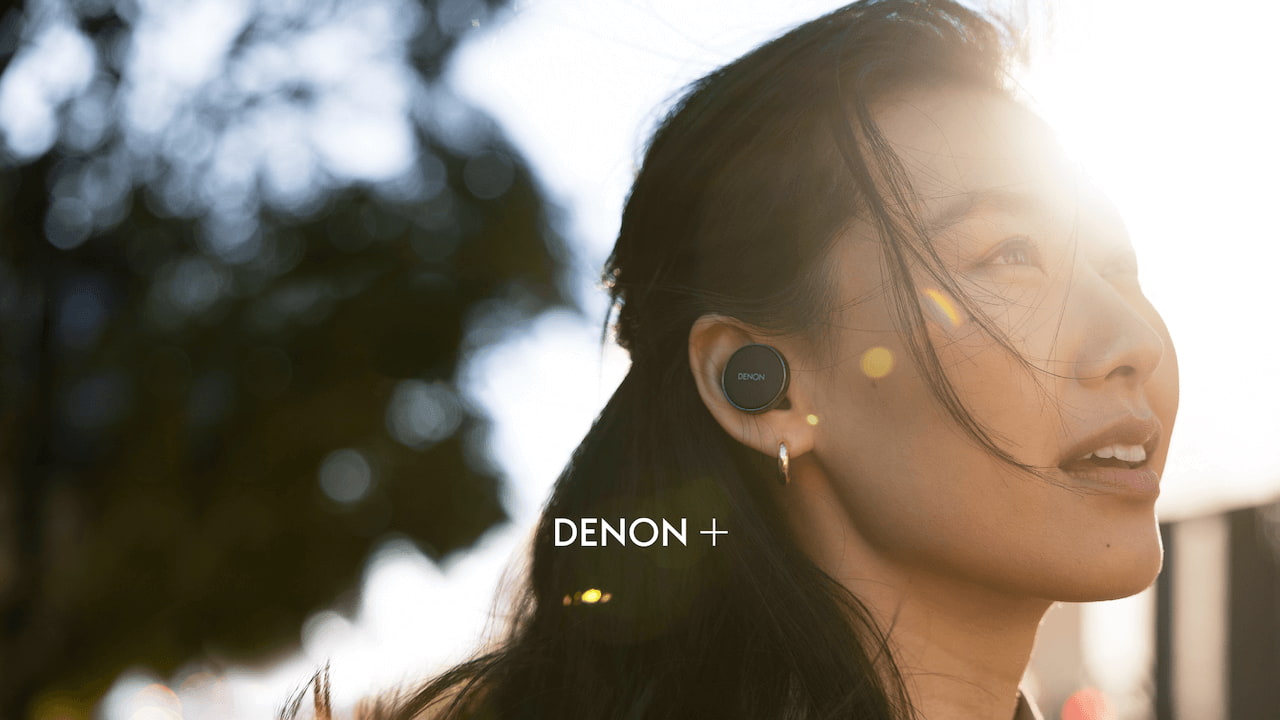 Woman wearing black Denon+ PERL wireless earbud for new subscription program