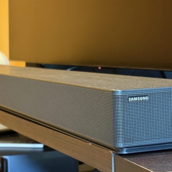 Samsung's HW-QS90H soundbar sits on a brown console below a black TV screen