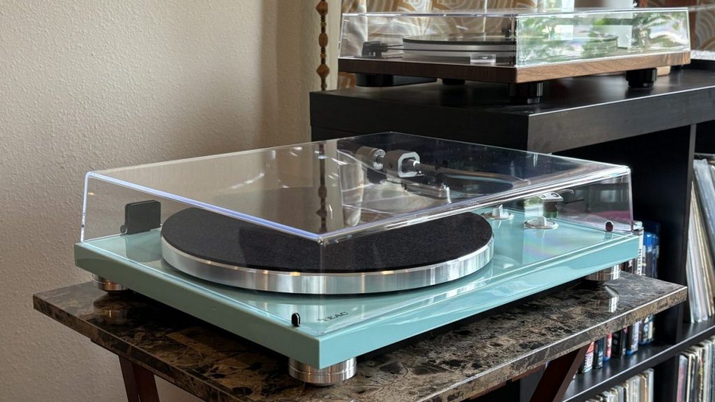 A turquoise TEAC TN-400BT-X turntable sits on a table next to a record console.